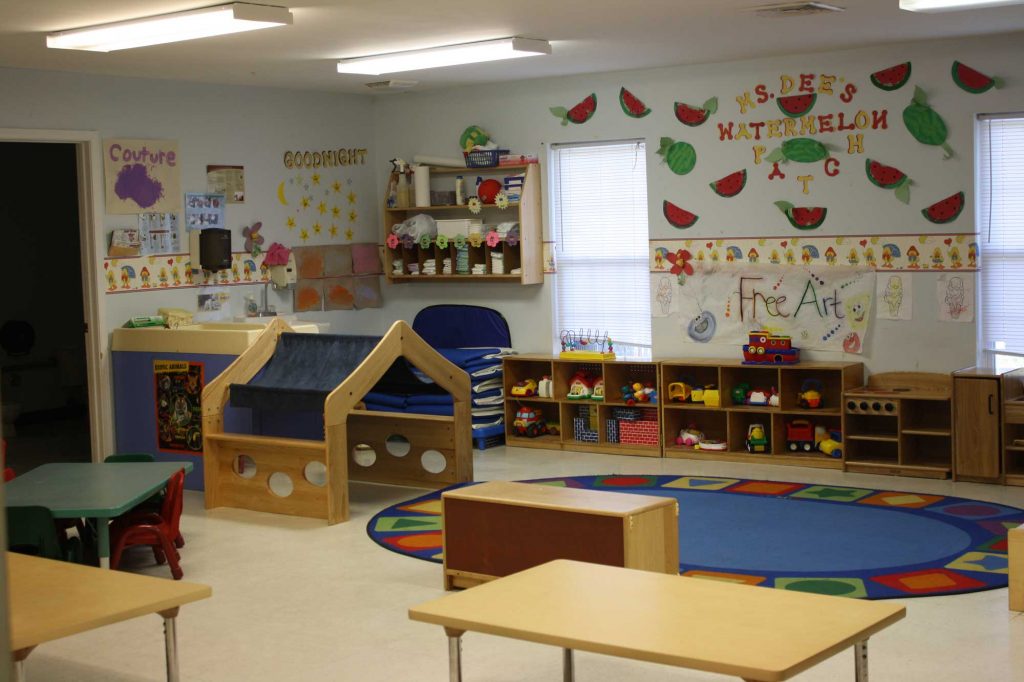 A view of a children's play school, with colorful toys scattered on the floor and educational posters on the walls